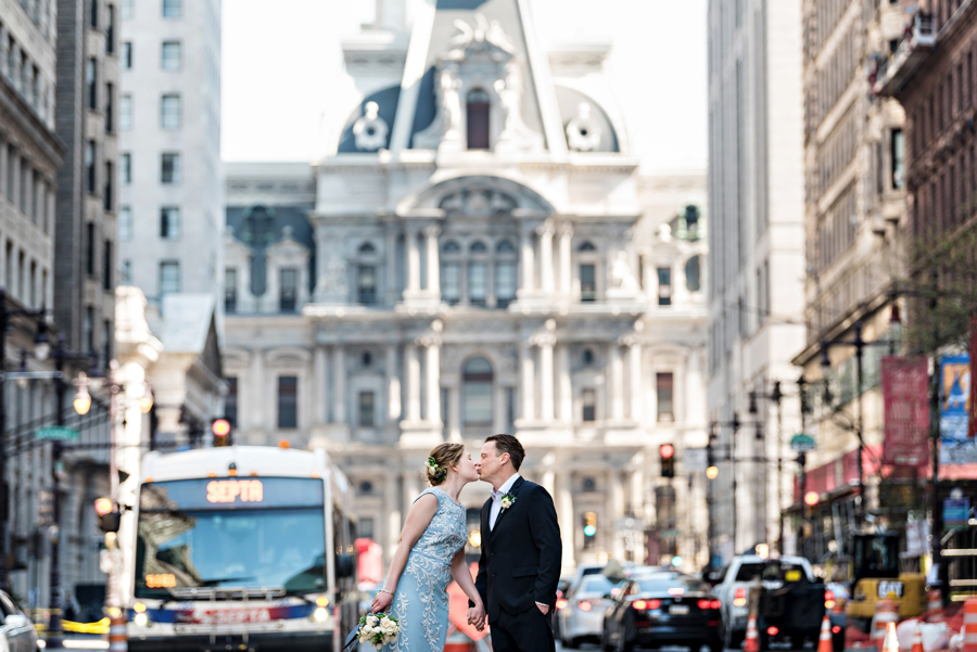 A wedding couple share a kiss in the middle of the busy intersection of Broad St and Chestnut St in Philadelphia.